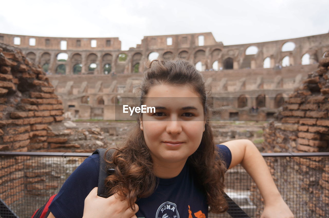 Portrait of young woman against historic building