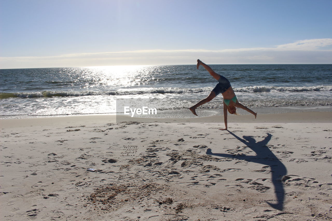 Woman doing cartwheel on sand at beach