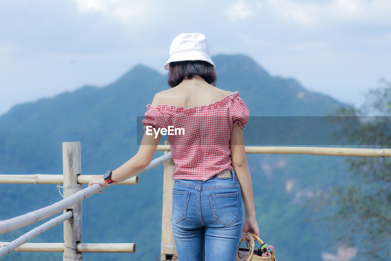 Woman standing by railing against mountain