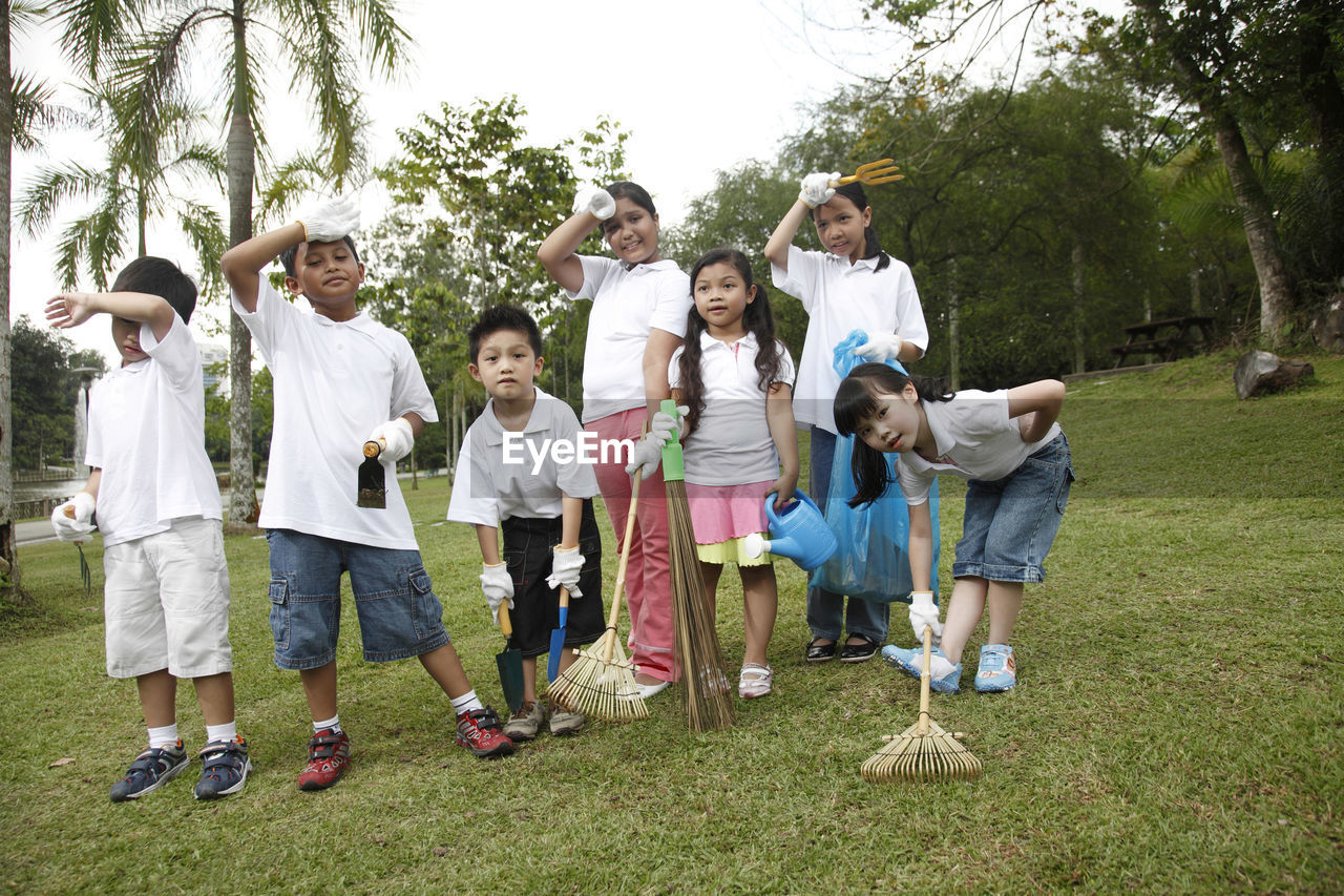 Tired friends cleaning park