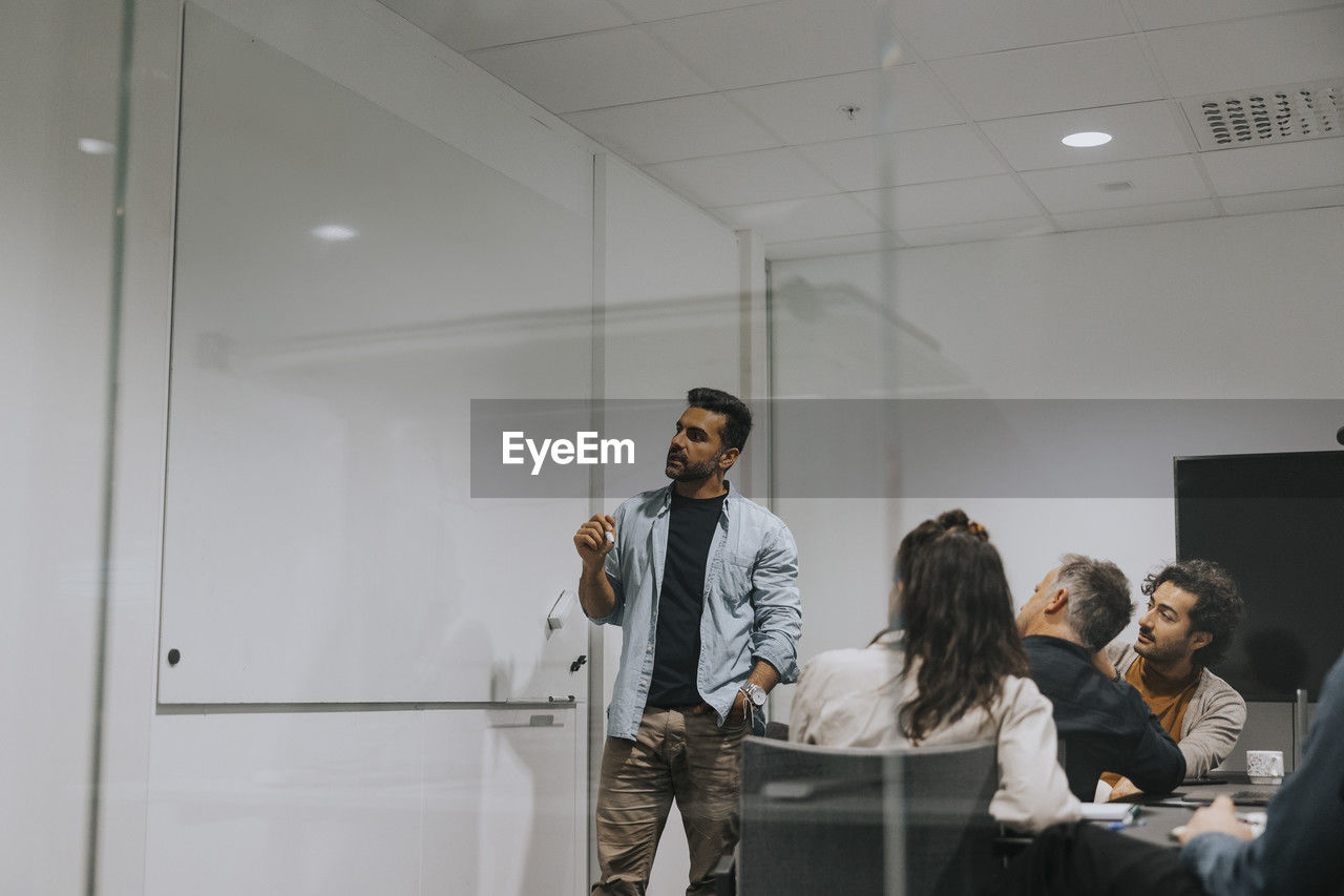 Businessman explaining strategy on whiteboard to colleagues in board room