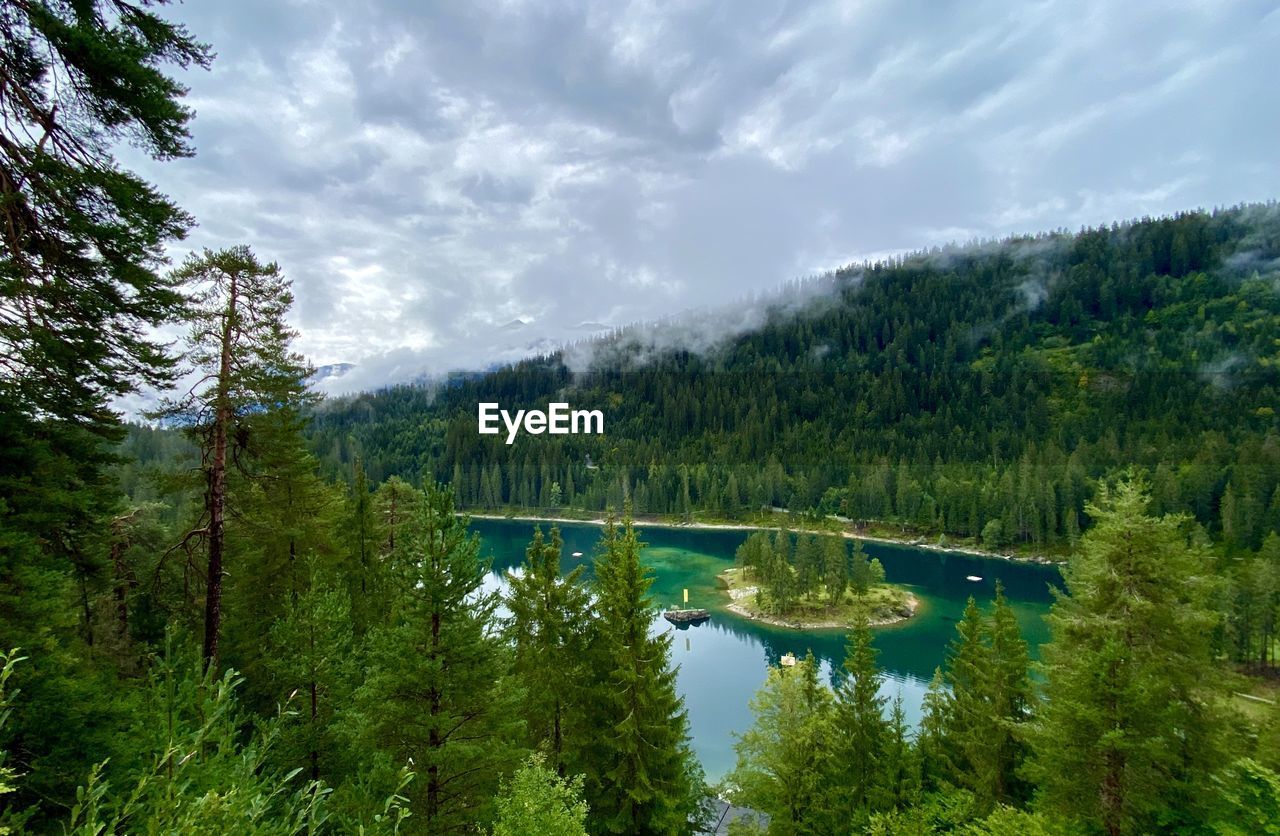 Scenic view of lake cauma with trees against a cloudy sky