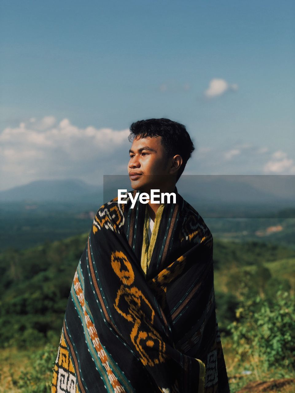 Young man looking away against sky