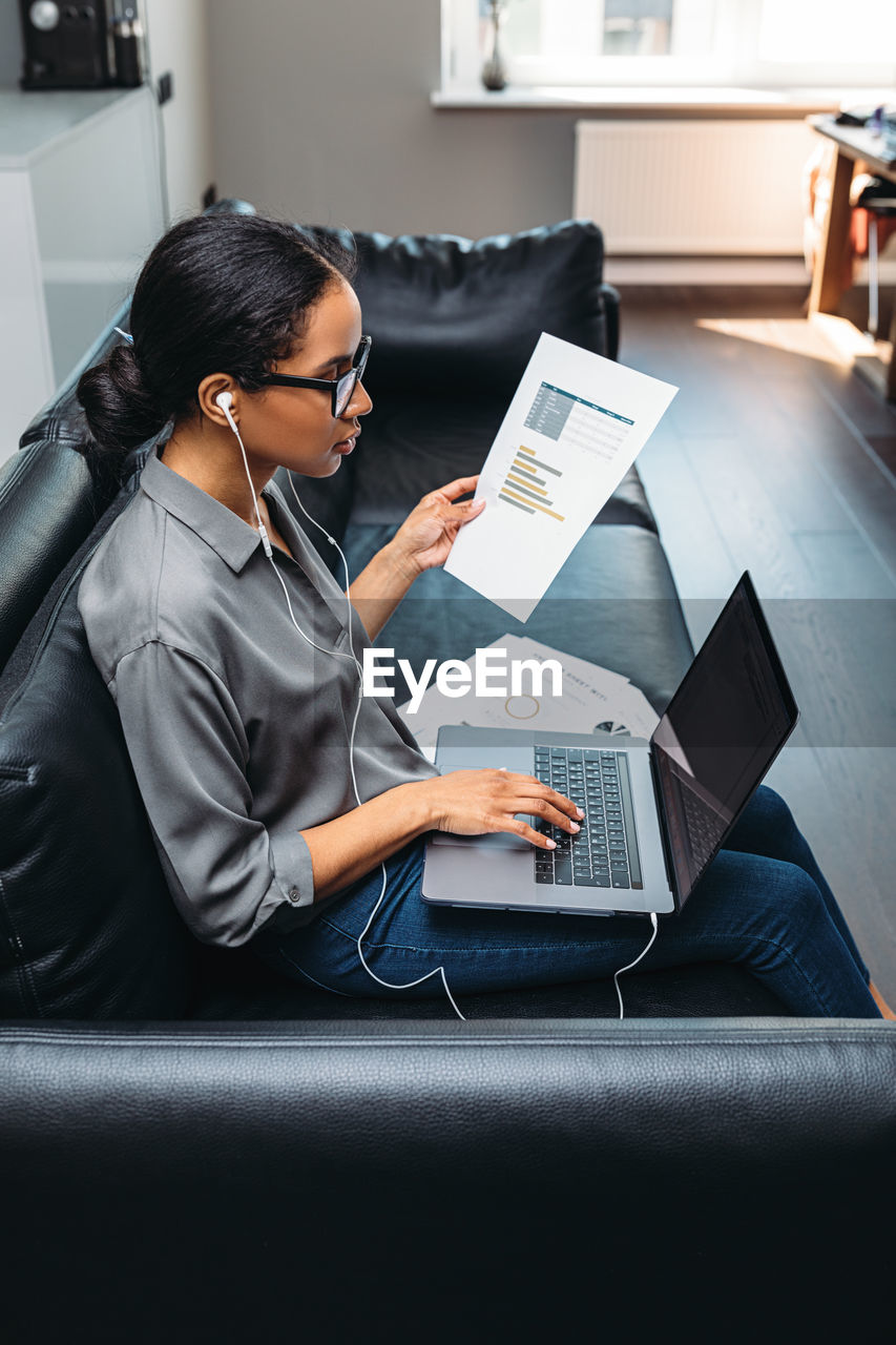 High angle view of woman using laptop while sitting on sofa