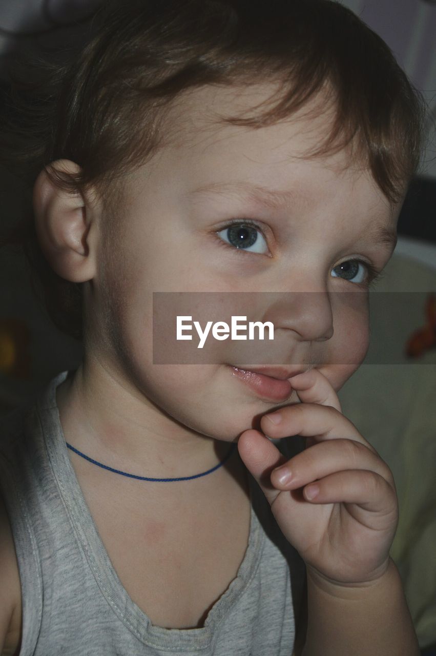 Close-up of cute baby boy with finger on lips looking away