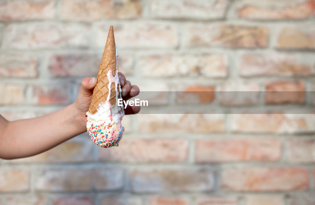 Close-up of hand holding ice cream against wall