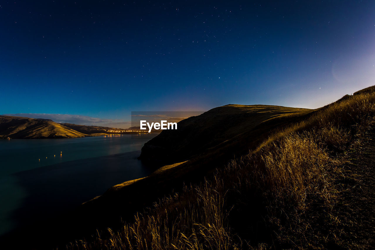 SCENIC VIEW OF LANDSCAPE AGAINST CLEAR BLUE SKY AT NIGHT