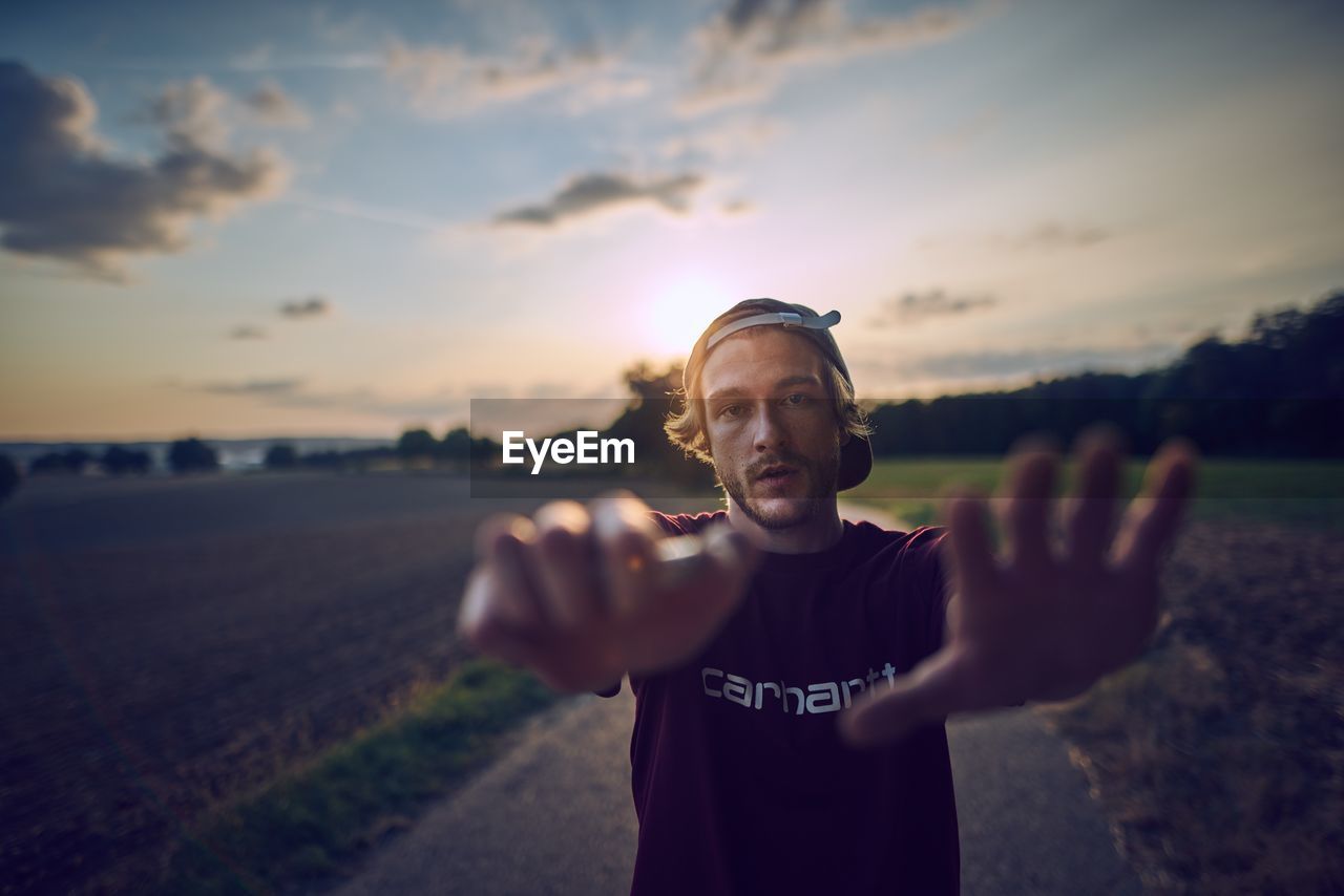 PORTRAIT OF MAN STANDING ON LAND AGAINST SKY