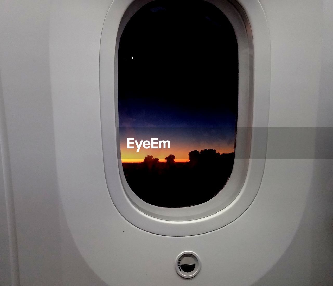 Close-up of airplane window against sky during sunset