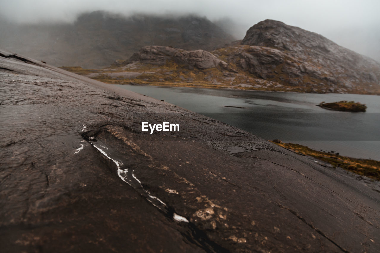 Scenic view of lake by mountain against sky