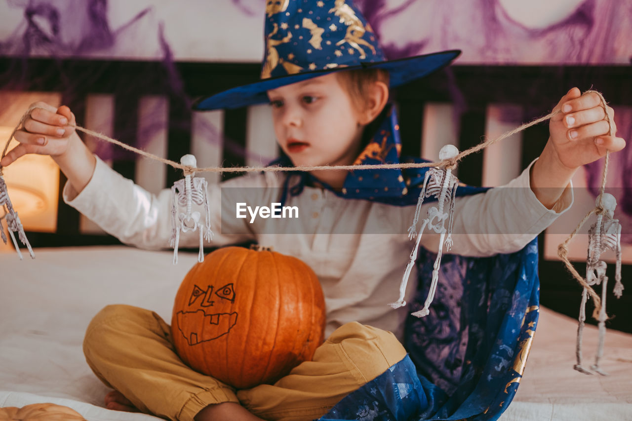 Cute little caucasian boy in a halloween costume with big orange pumpkin jack-o-lantern.