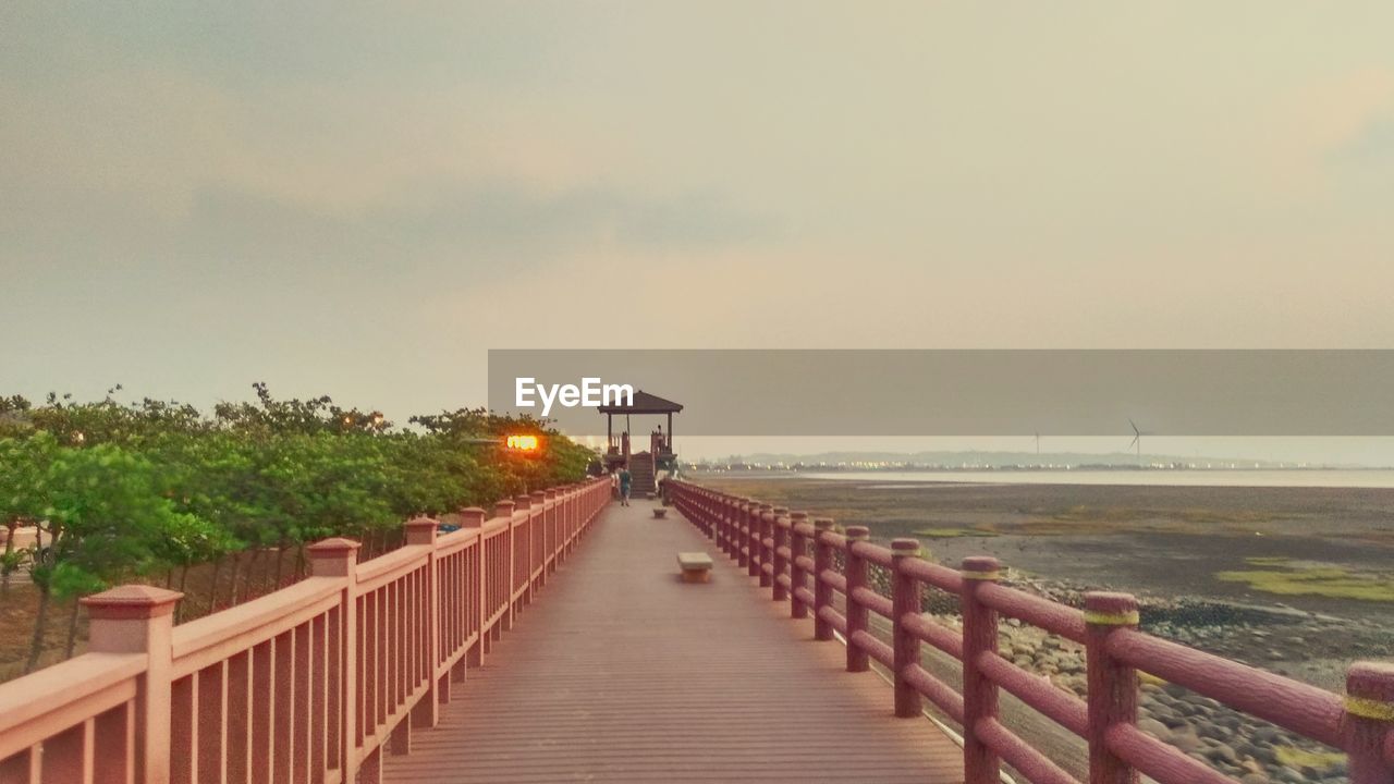 WALKWAY LEADING TOWARDS SEA AGAINST CLEAR SKY