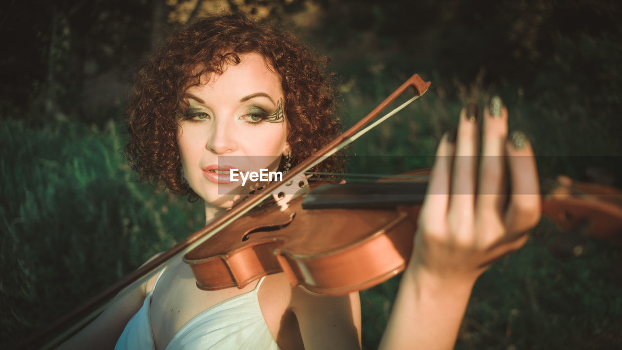 Close-up of woman playing violin while standing on field