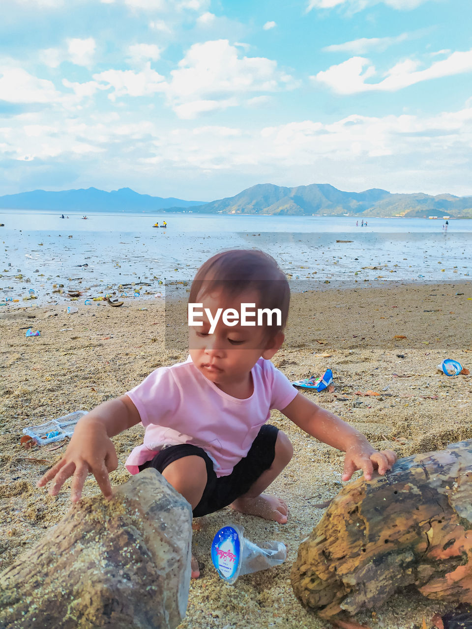 land, childhood, beach, child, one person, water, sea, vacation, nature, sand, sky, leisure activity, full length, shore, female, day, coast, ocean, holiday, toddler, lifestyles, body of water, women, innocence, casual clothing, beauty in nature, trip, rock, person, cute, outdoors, front view, looking, smiling, cloud, happiness, scenics - nature, emotion, portrait, men, enjoyment, fun