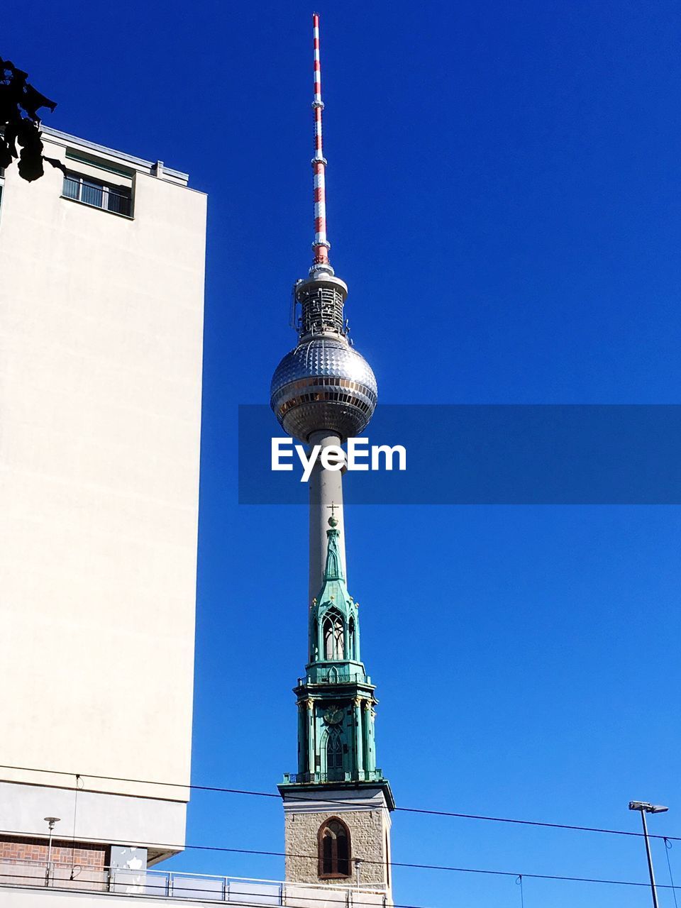 LOW ANGLE VIEW OF COMMUNICATIONS TOWER AGAINST BUILDINGS