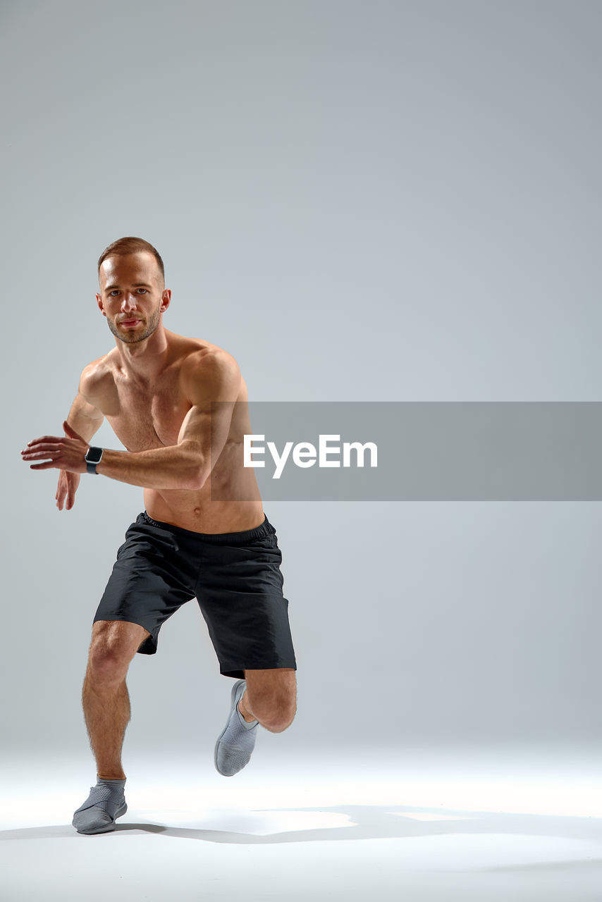 full length of young man exercising against clear sky