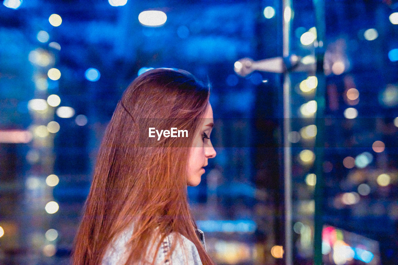 Woman looking down by glass window at night