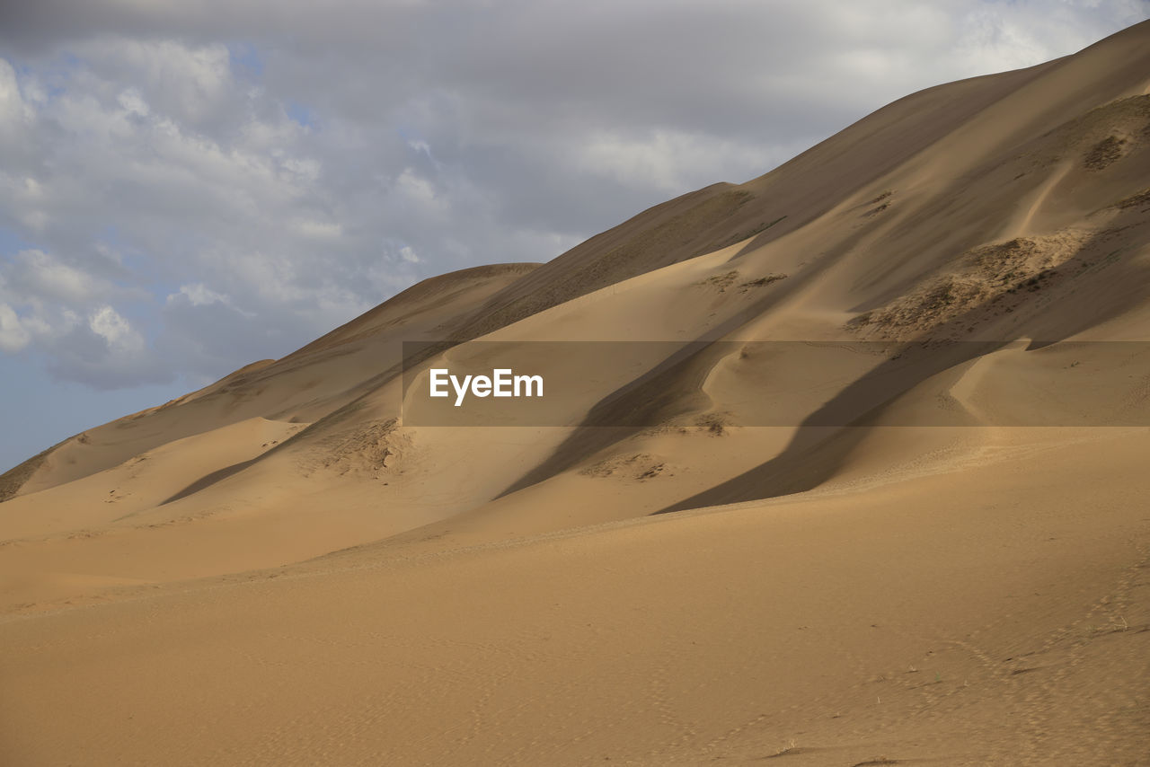 scenic view of desert against cloudy sky