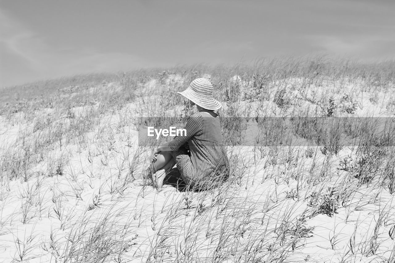 Scenic view of field against sky with woman using hat