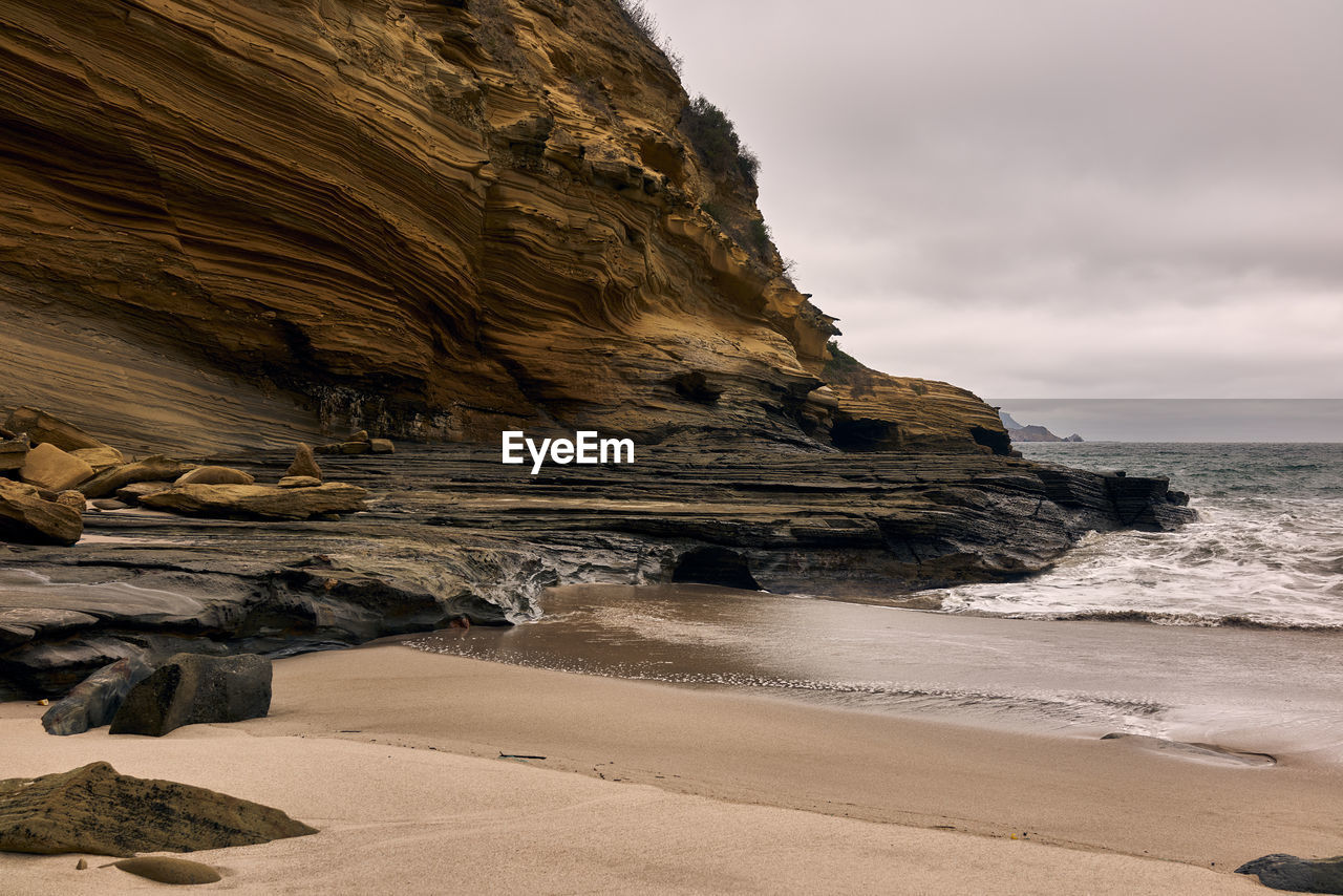 Rock formations on beach against sky