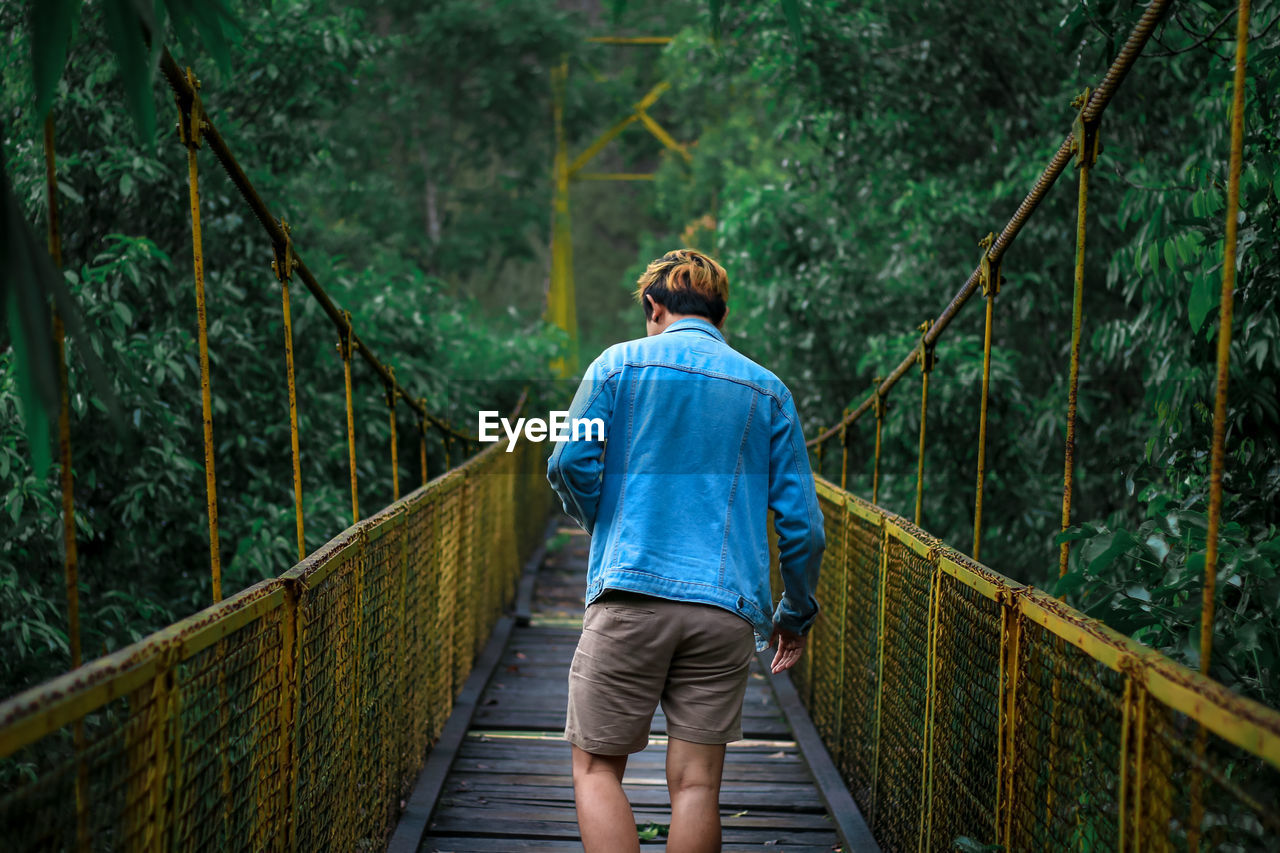 Rear view of man walking on footbridge