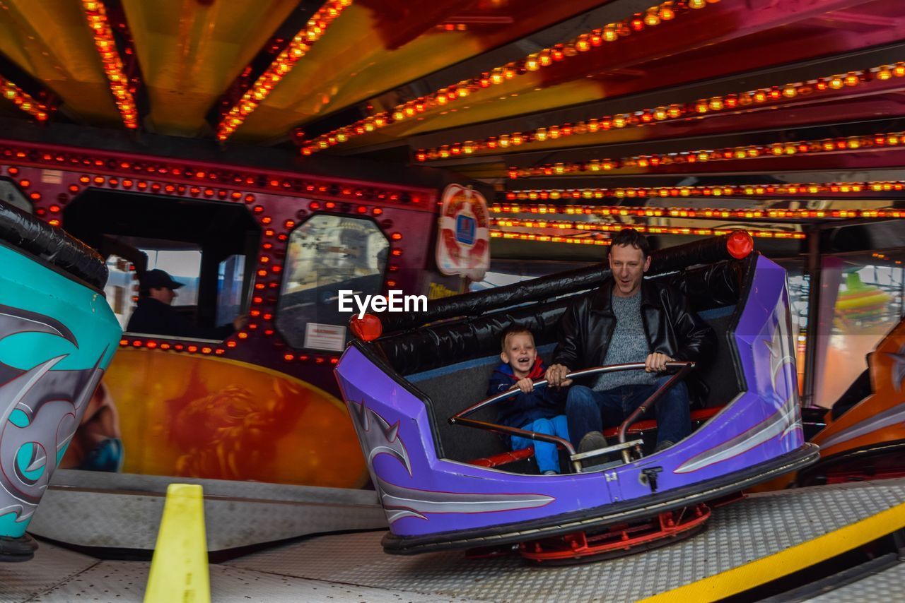 Father with son enjoying carousel at amusement park