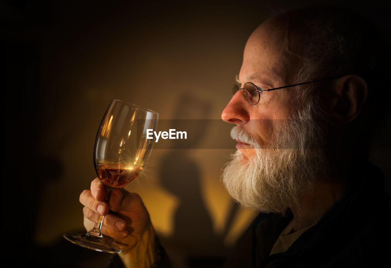 Close-up of bearded senior man holding alcoholic drink
