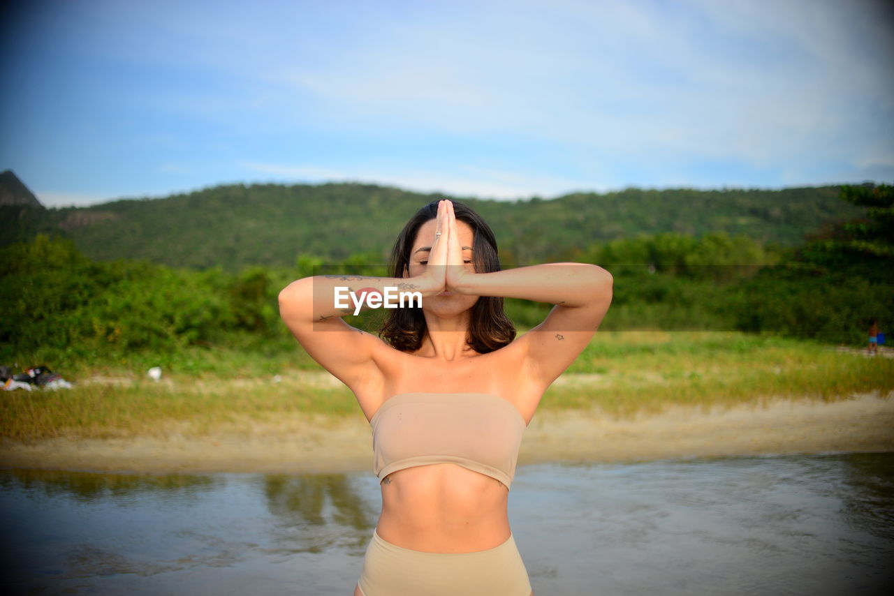 Beautiful woman meditating against sky