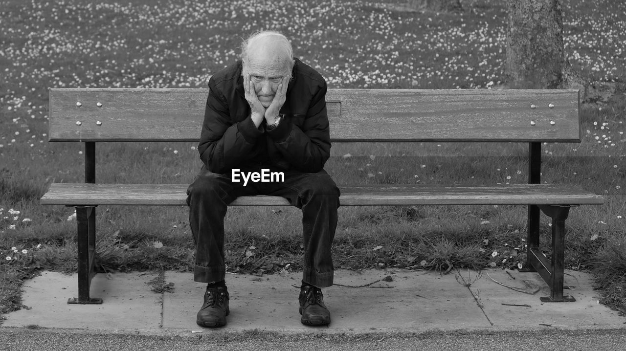 Full length of senior man sitting on bench in park