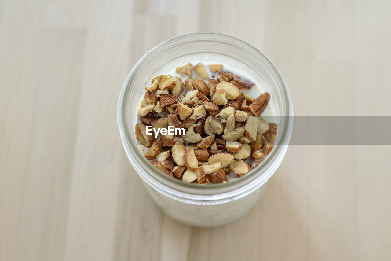 High angle view of almonds on oatmeal in jar at wooden table