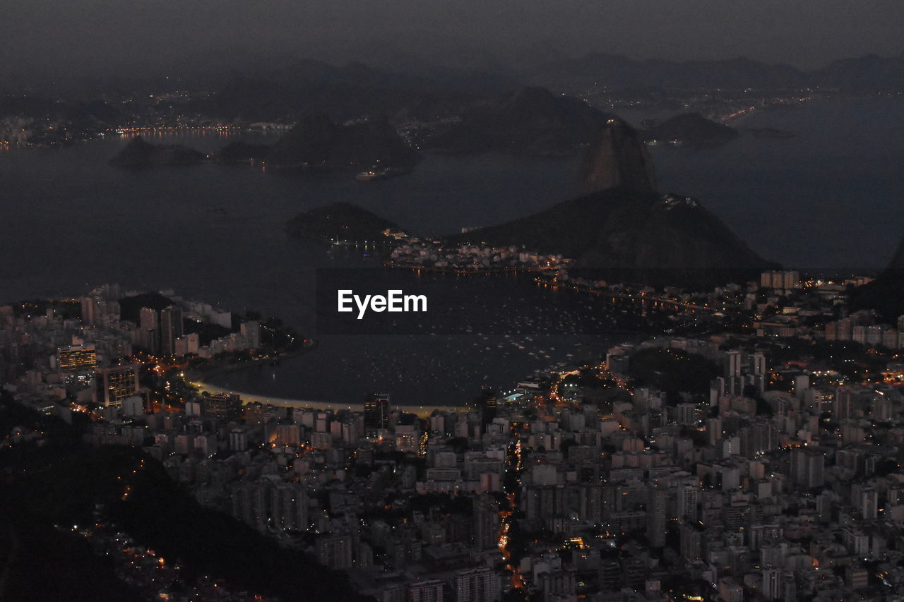 High angle view of illuminated city by sea