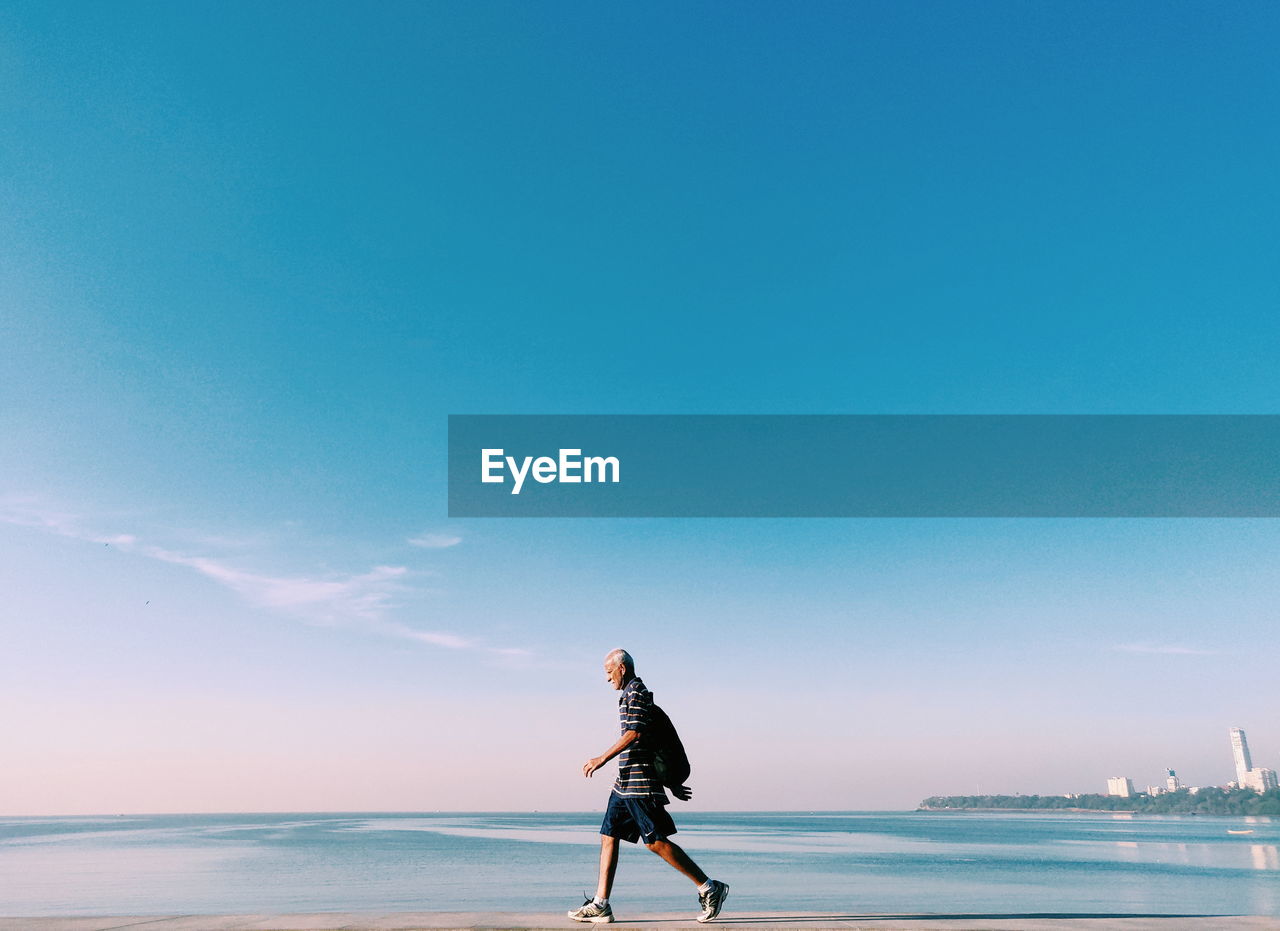 MAN ON BEACH AGAINST SKY