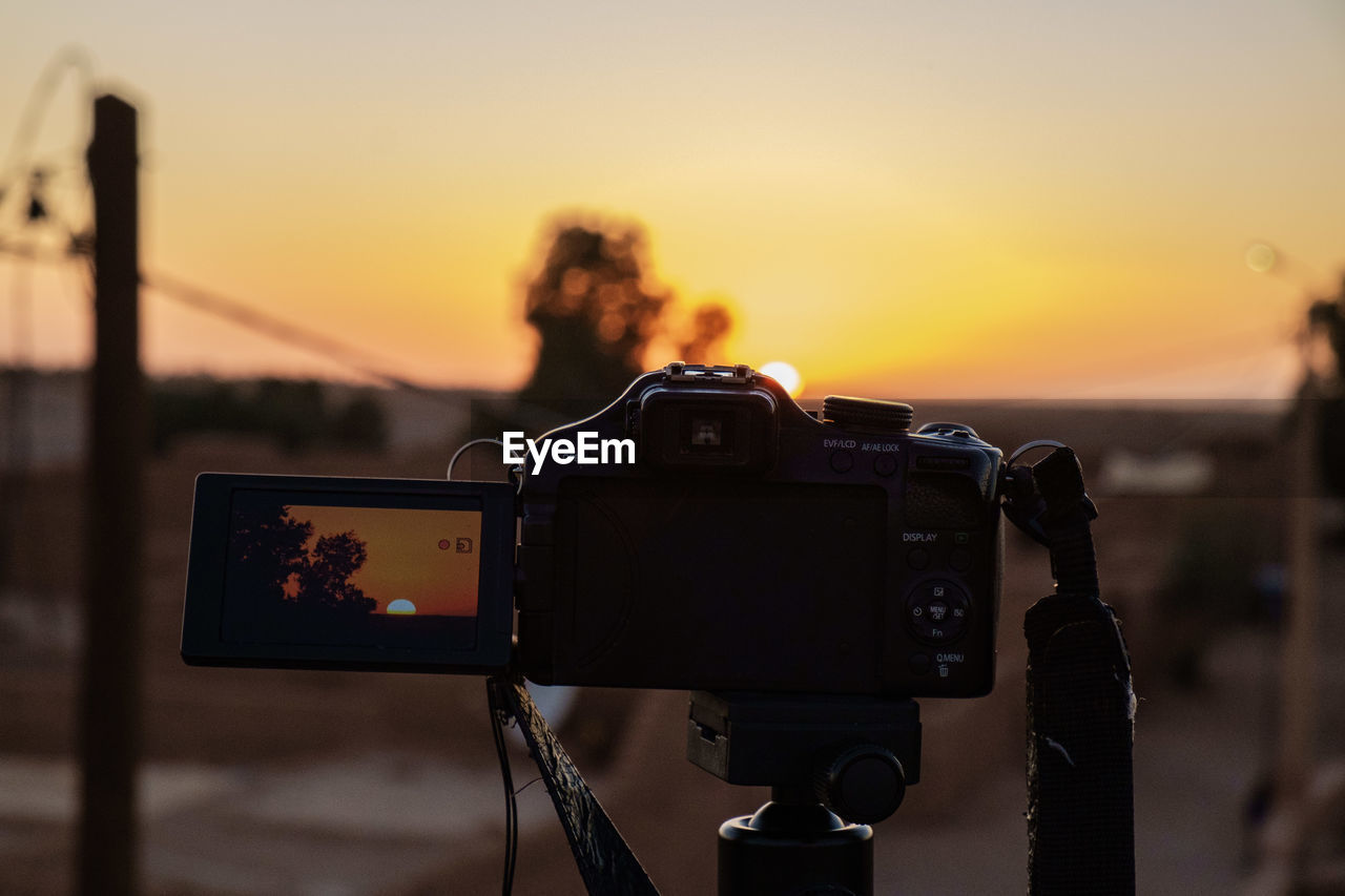 Close-up of camera against sky during sunset