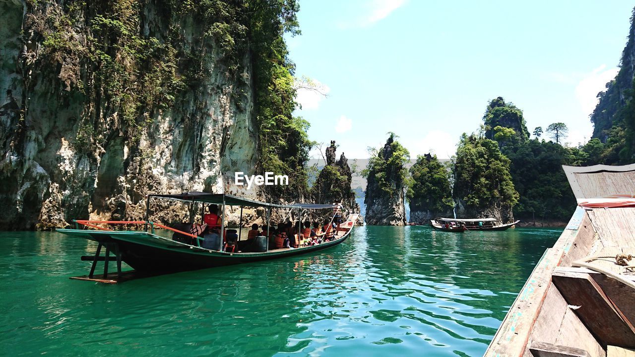 People in boats sailing on river against sky