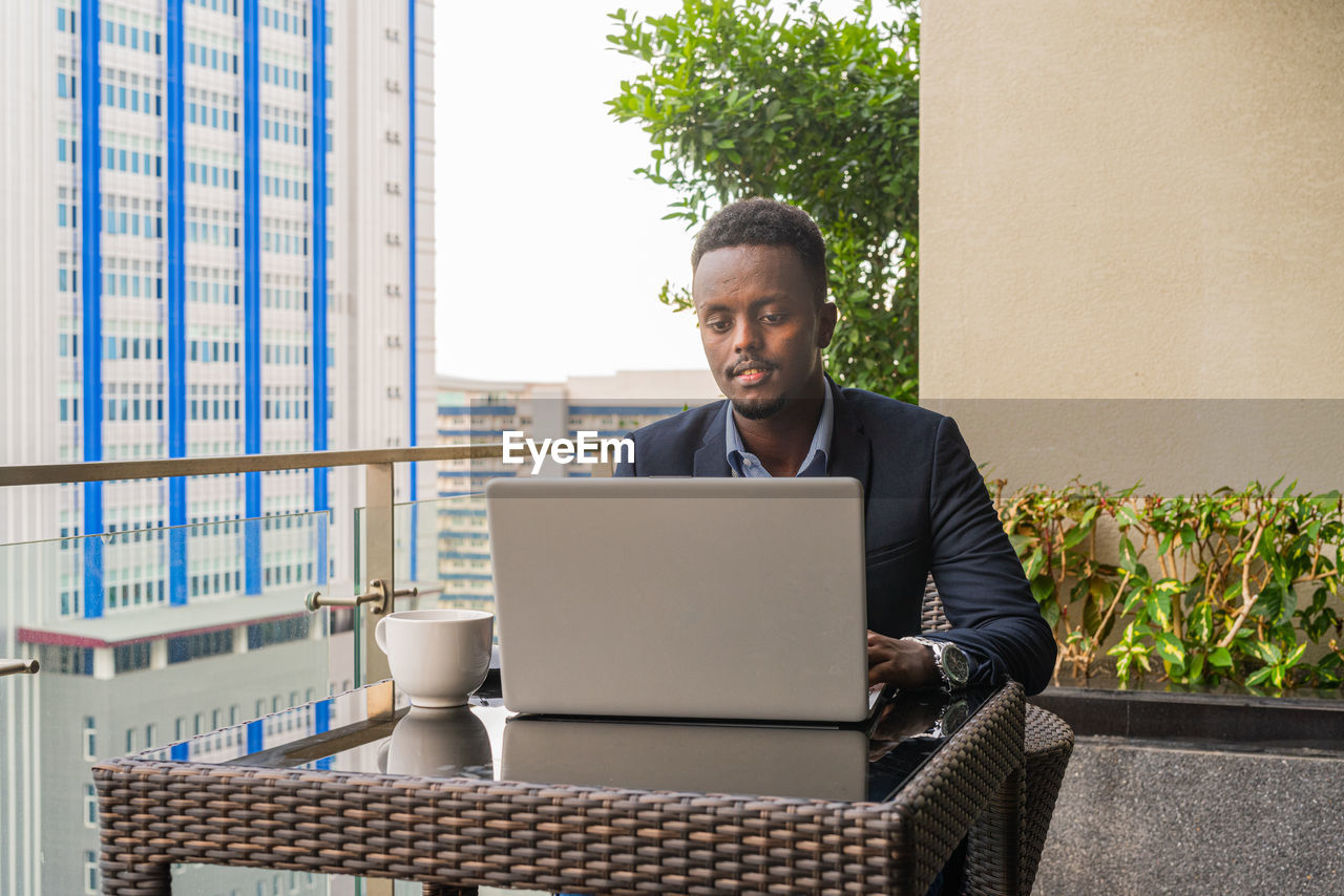 portrait of man using laptop while sitting on sofa at home