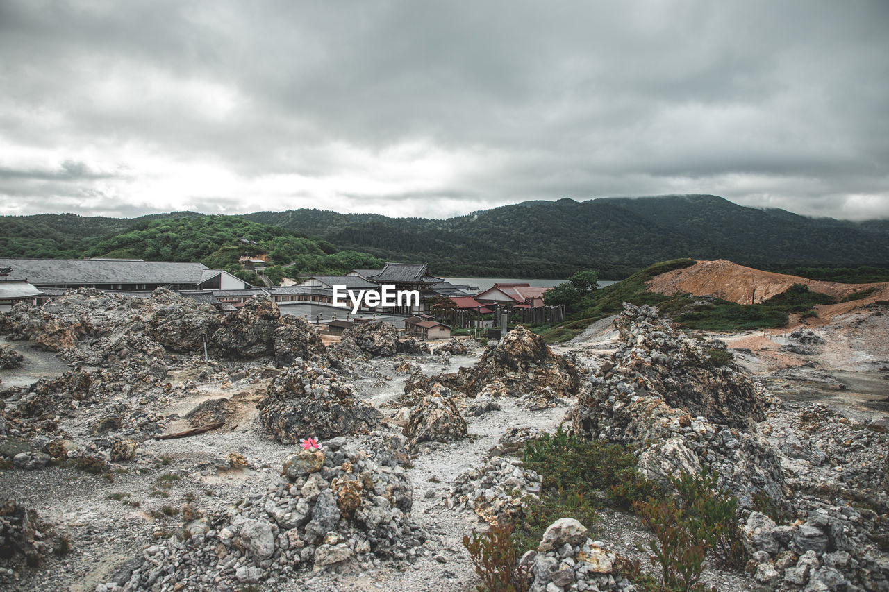 cloud, environment, sky, mountain, landscape, nature, sea, land, scenics - nature, coast, architecture, rock, overcast, no people, building, outdoors, beauty in nature, mountain range, built structure, travel destinations, travel, day, geology, water, building exterior, storm, non-urban scene, village