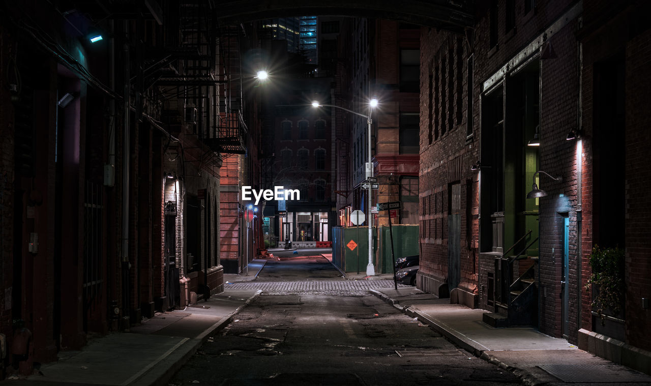 EMPTY ROAD AMIDST BUILDINGS AT NIGHT