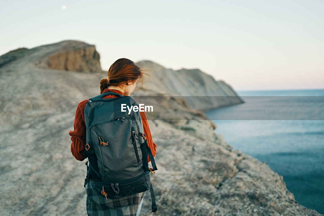 REAR VIEW OF MAN LOOKING AT SEA