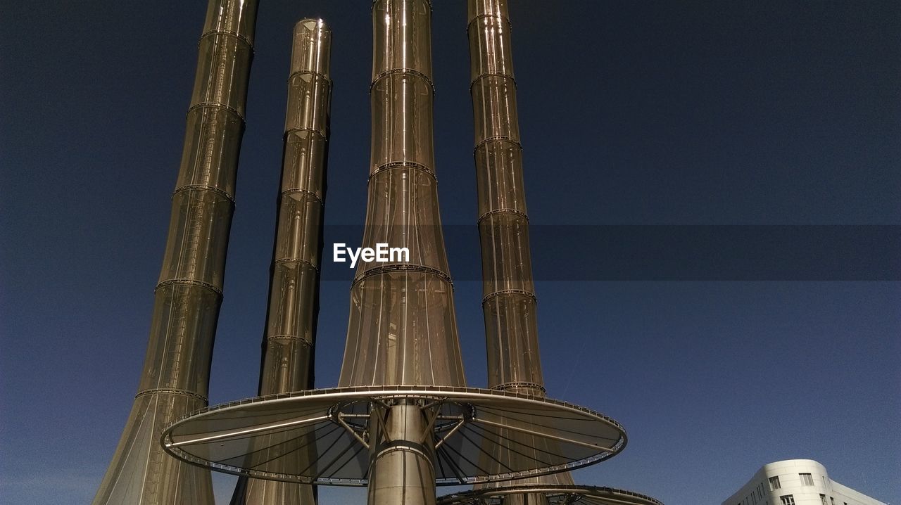Low angle view of smoke stacks against clear sky