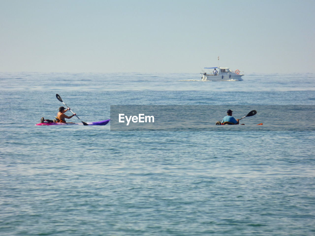 Men canoeing in sea against sky