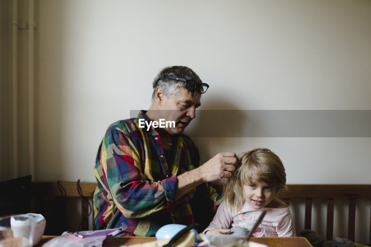 Grandfather helping granddaughter with her hair