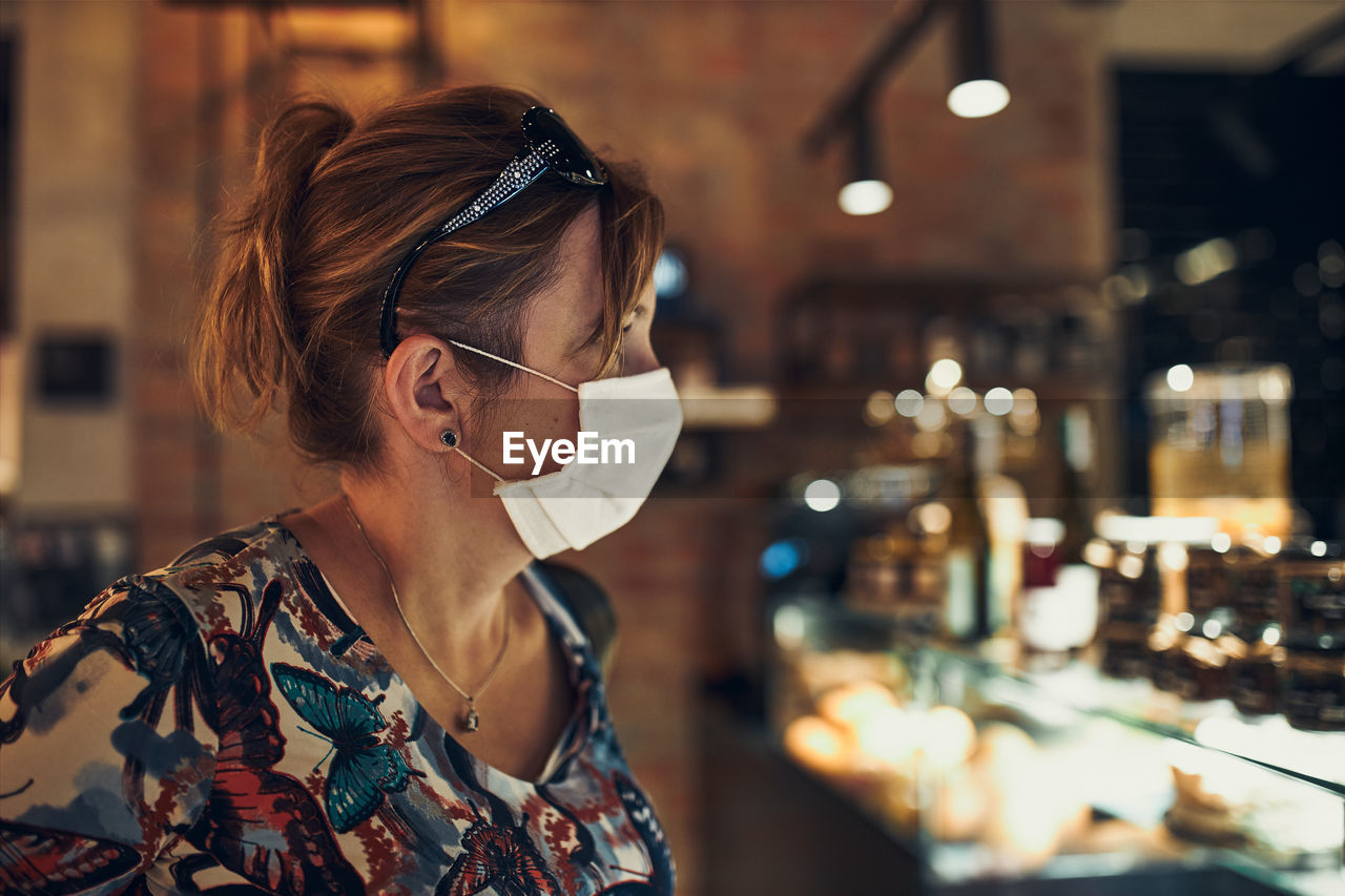 Woman wearing flu mask standing in cafe