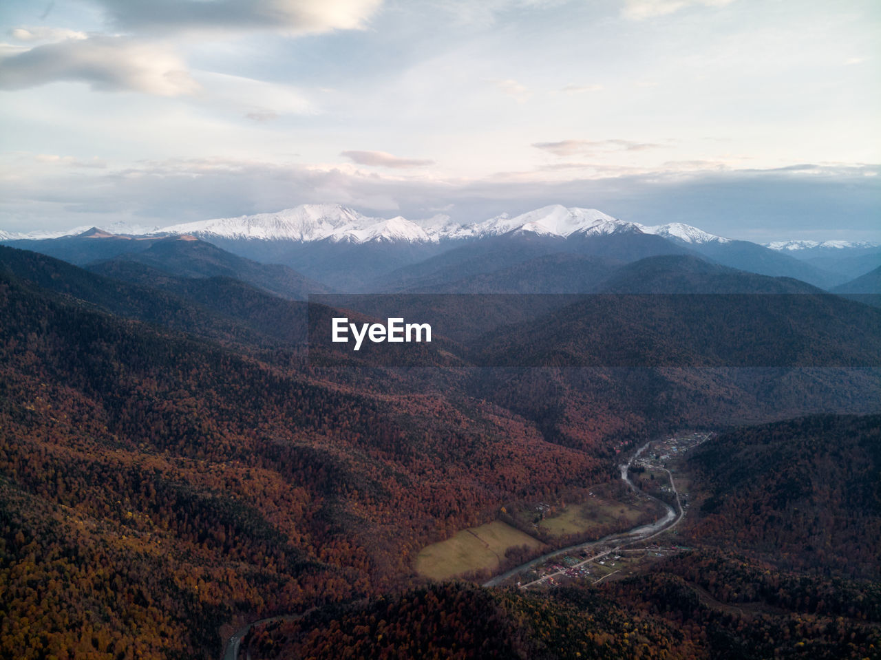 Aerial view, sea of fog and clouds illuminated by the rising sun, snow on the tops of the mountains