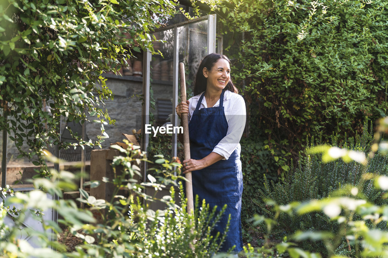 Smiling mature woman looking away while standing in back yard