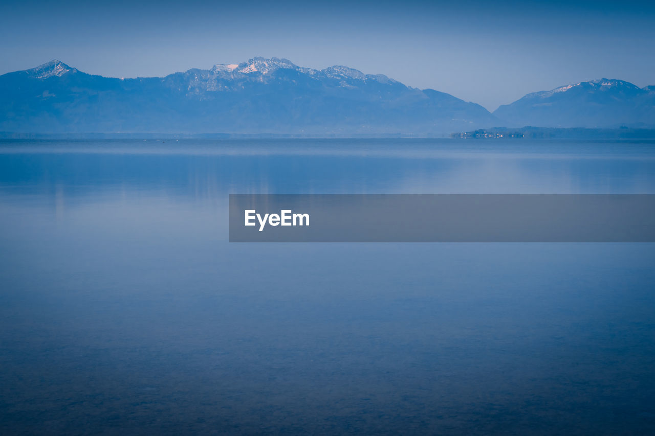 Scenic view of lake and mountains against blue sky