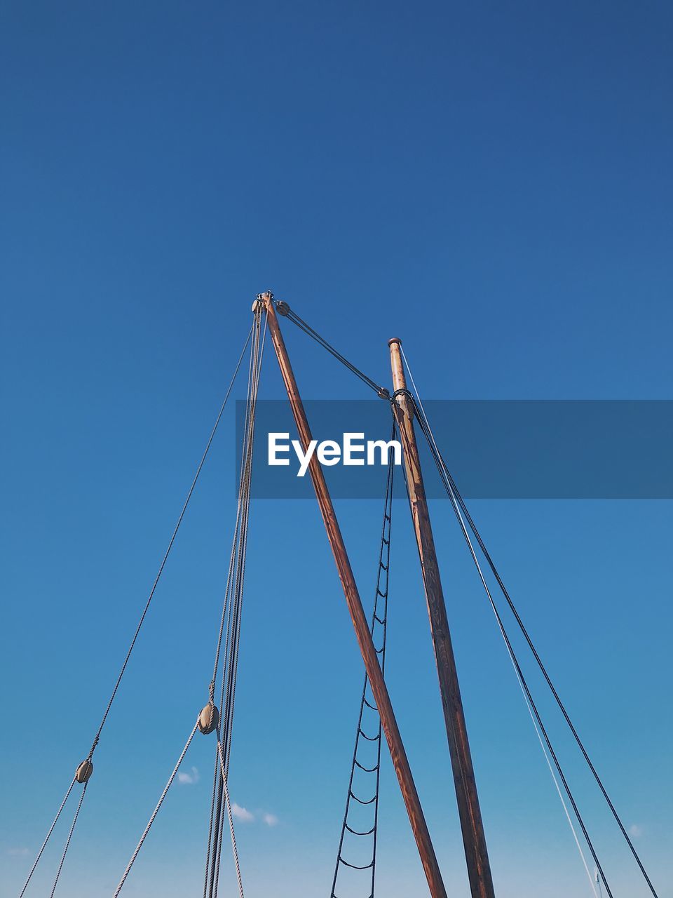 Low angle view of ship cables against clear blue sky