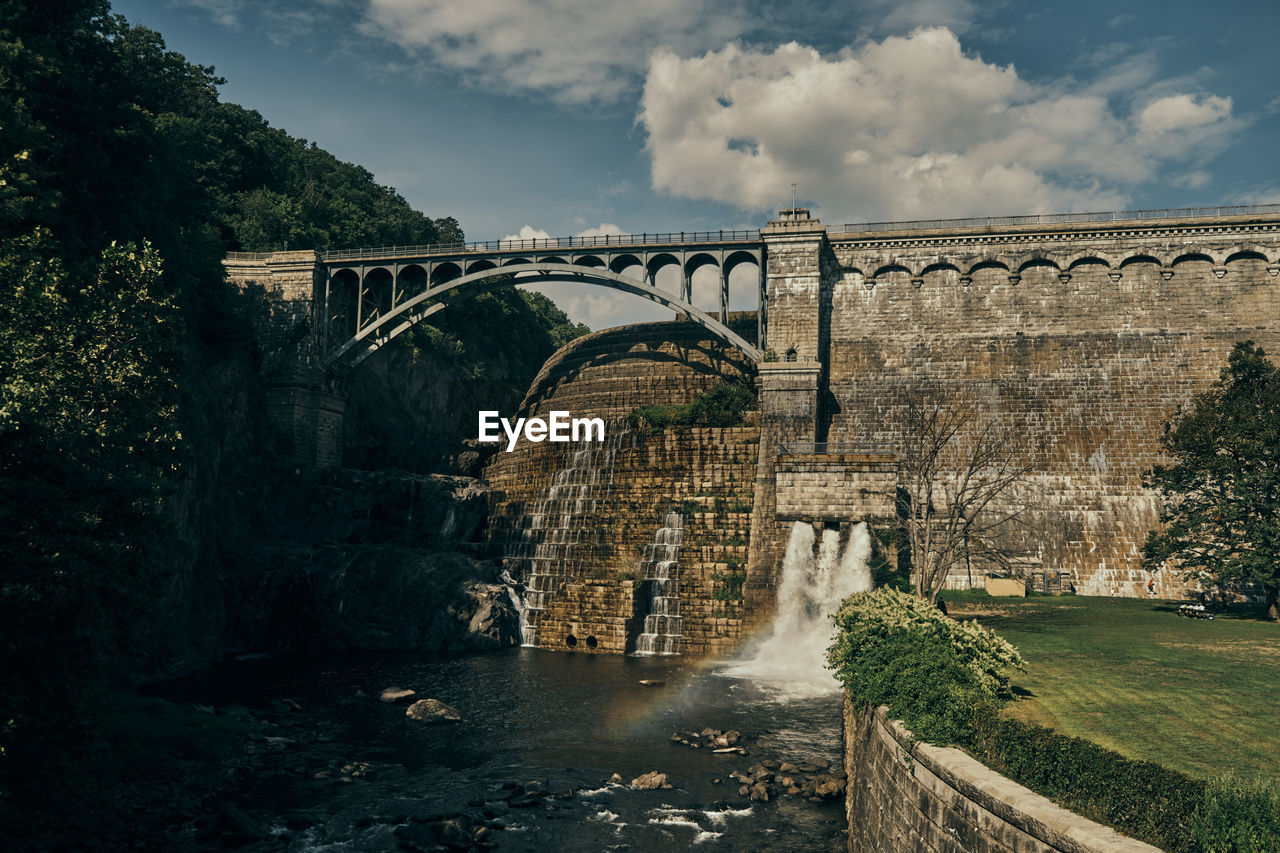 Arch bridge over river against sky