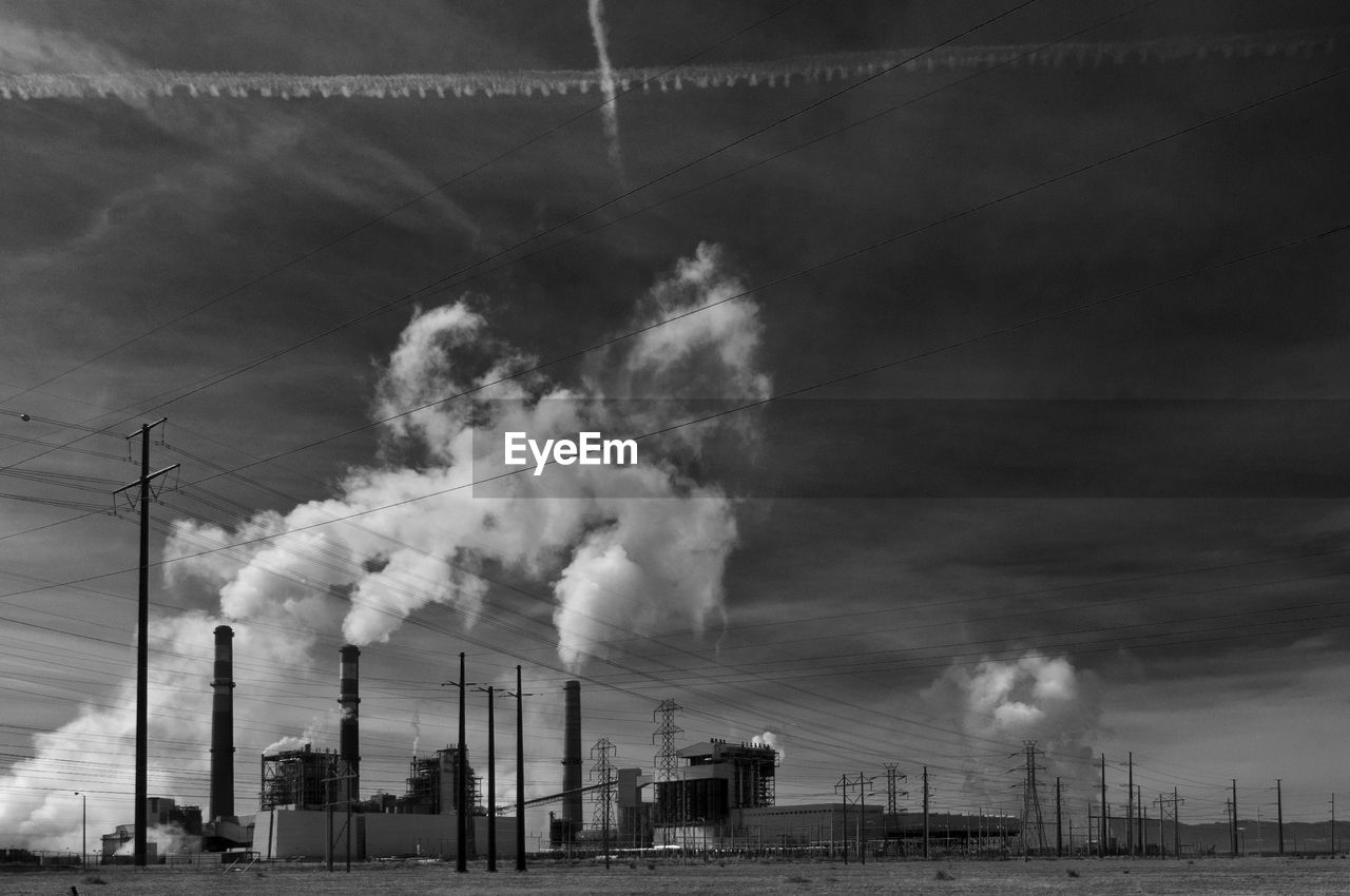 Smoke stack emitting pollution from factory against sky