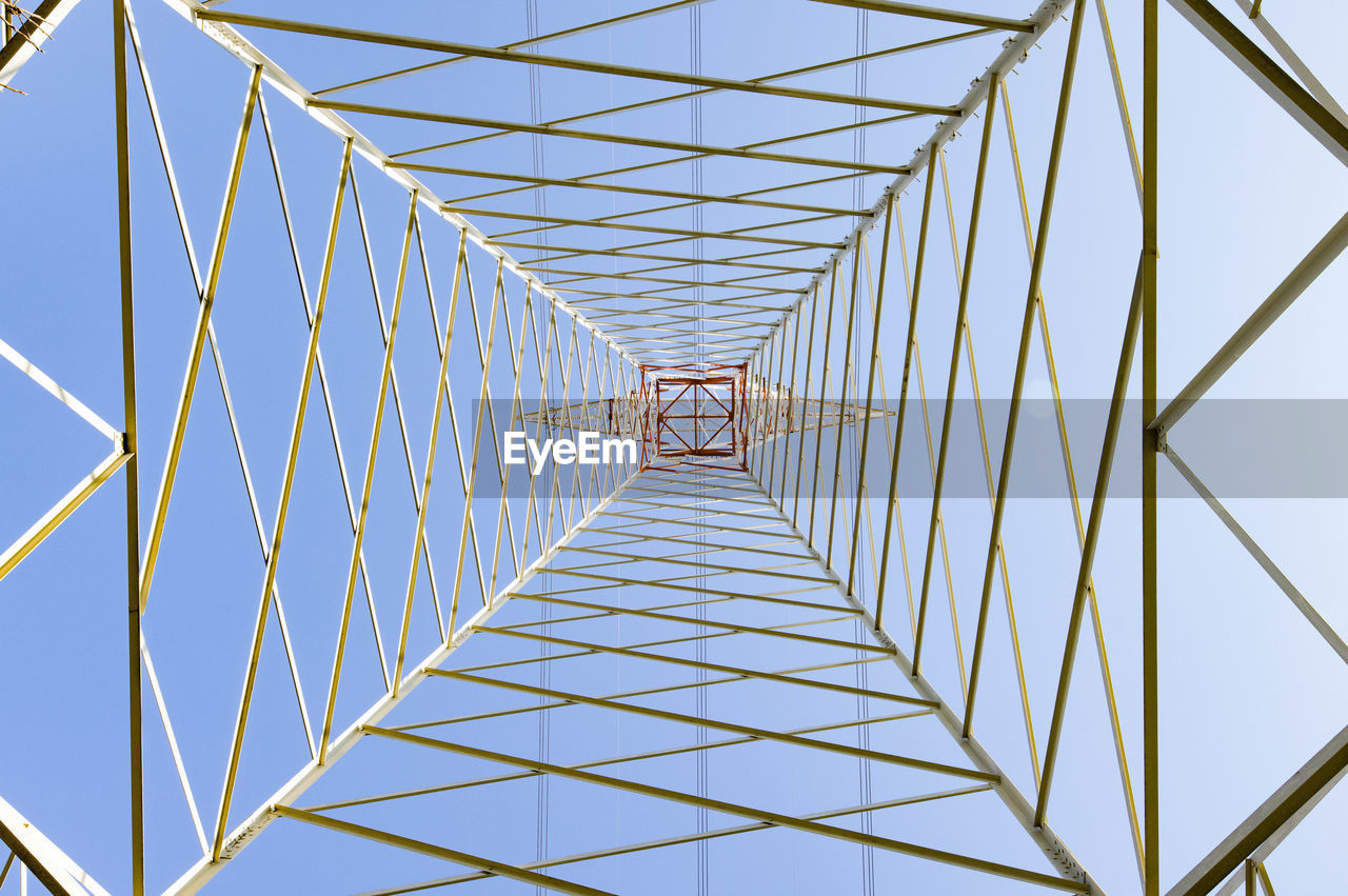 Electricity pylon in perspective seen from below with blue sky background