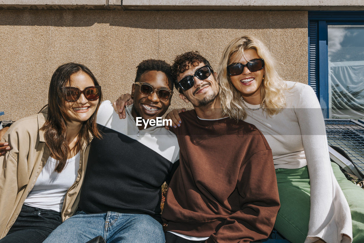 Portrait of happy male and female students wearing sunglasses at college campus
